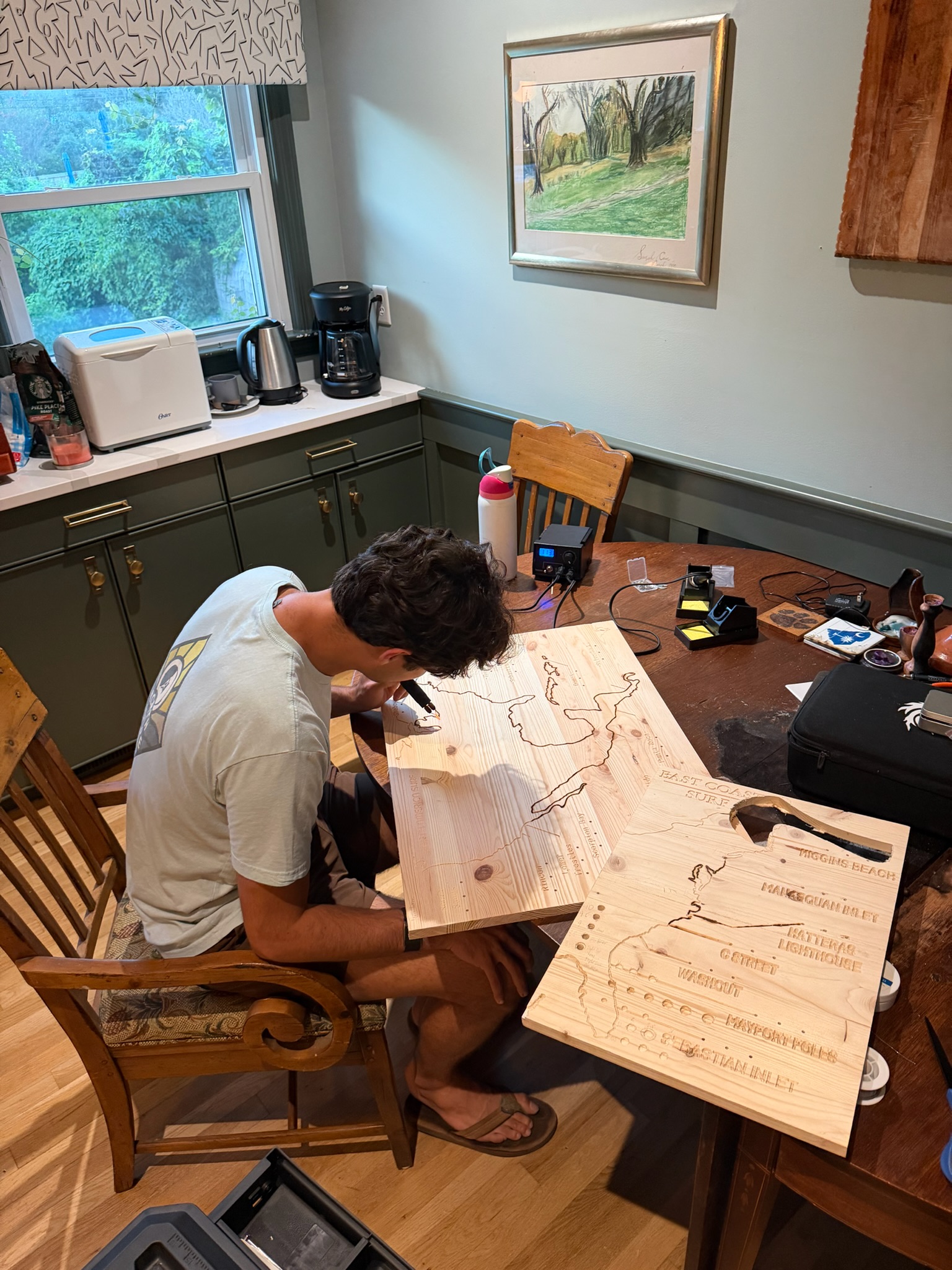 Wood-burning a coastline into a pine map at the kitchen table.